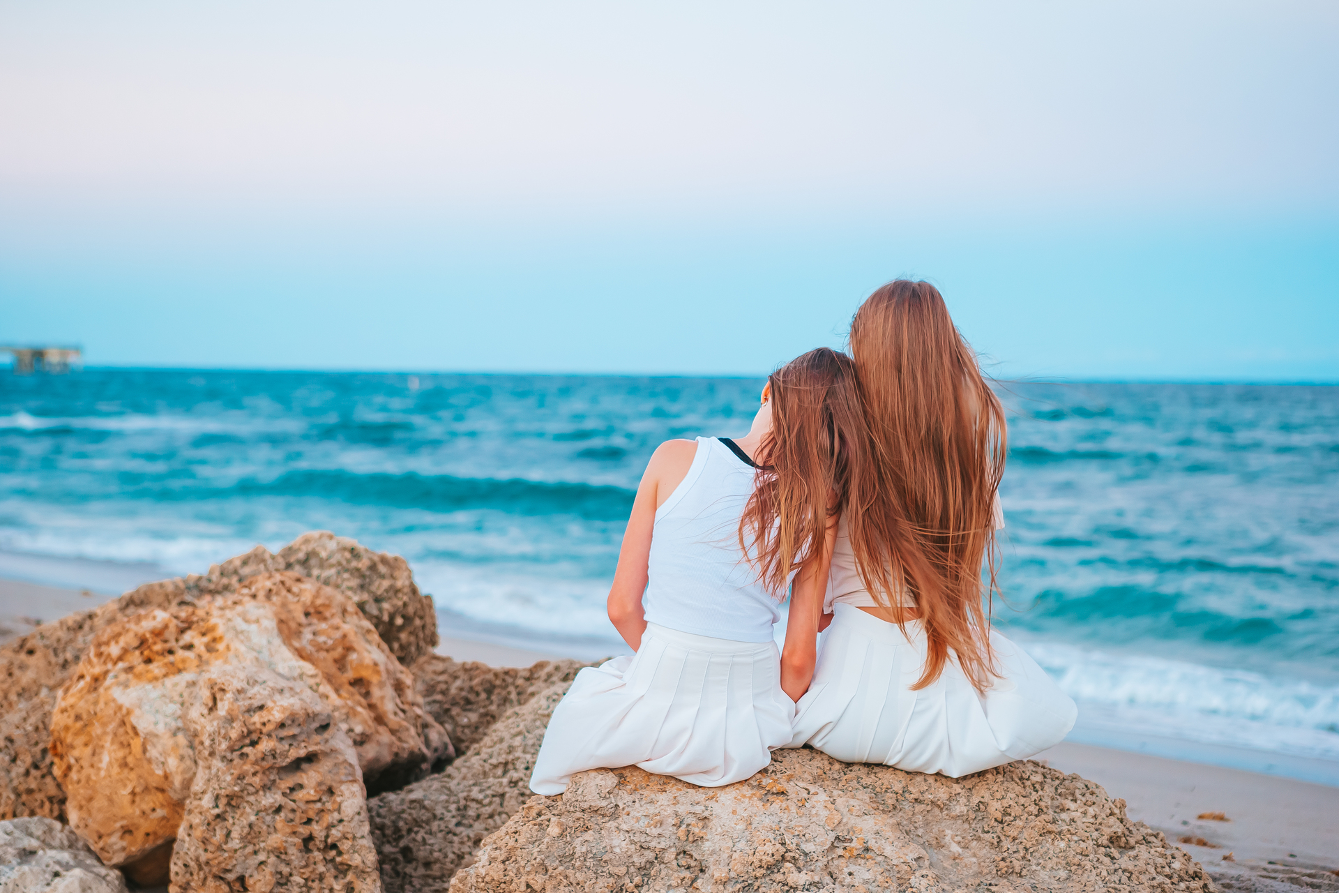 Dwie przytulające się siostry na brzegu morza